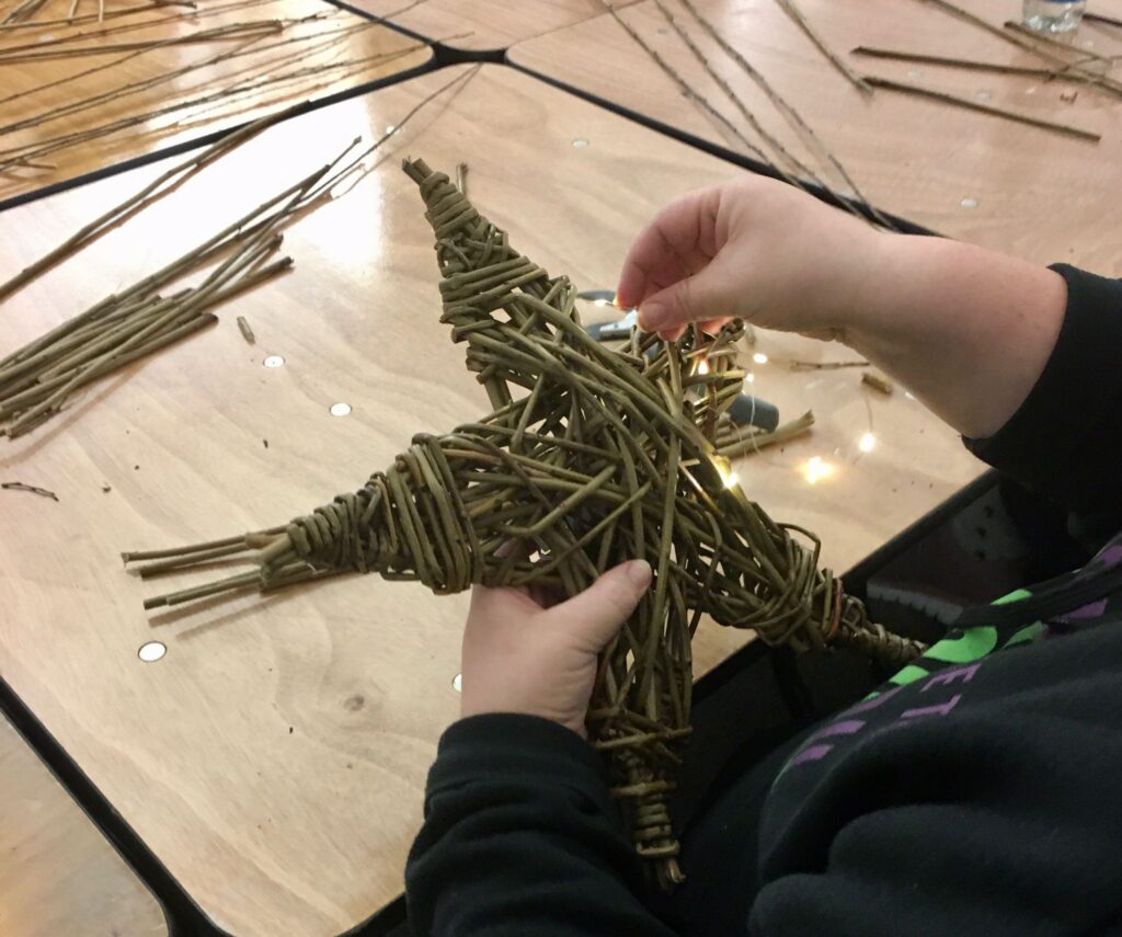 Someone creating a willow star - you can just seen their hands and materials.