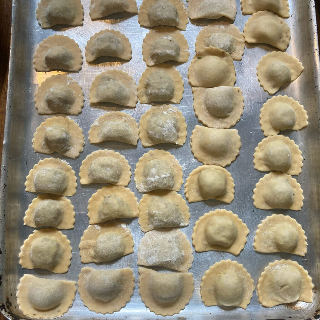 Photo of a tray of dumplings looking like mini Cornish pasties, with crimped edges. Not yet cooked.